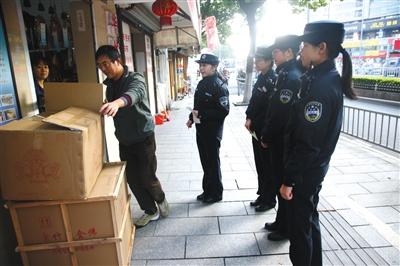 2015年12月3日，浙江宁波，江东区城管执法局女子执勤组首次亮相。百丈路上一位商户面对微笑执法的女队员，很配合地把摆在人行道上的货品收进店里。图/视觉中国