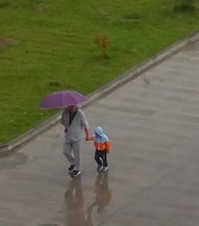 这张“奶奶给孙子打伞”照片火了 孩子一脸蒙圈：我的伞呢?