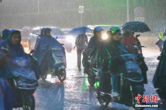 资料图为民众冒雨出行。中新社记者 骆云飞 摄