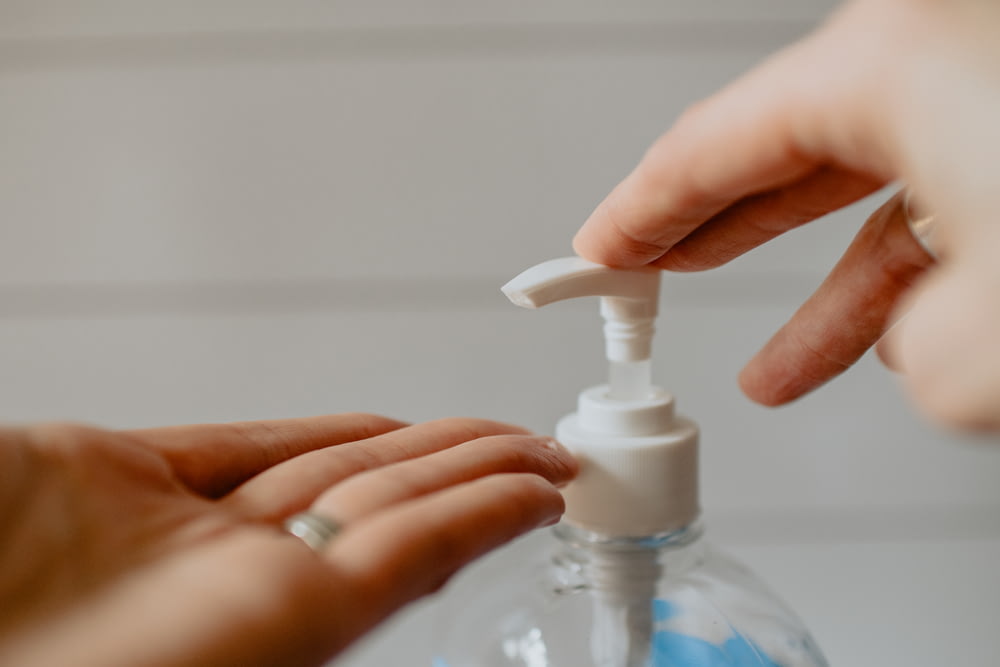 person holding white plastic pump bottle